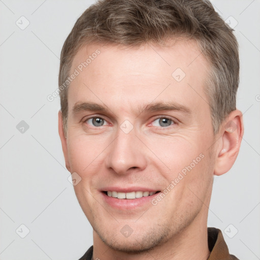 Joyful white young-adult male with short  brown hair and grey eyes