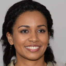 Joyful black young-adult female with long  brown hair and brown eyes