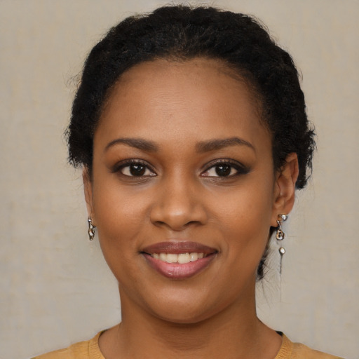 Joyful black young-adult female with short  black hair and brown eyes