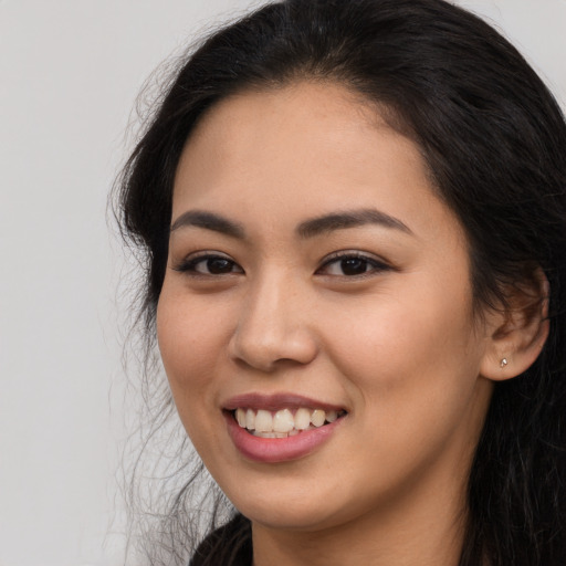 Joyful latino young-adult female with long  black hair and brown eyes