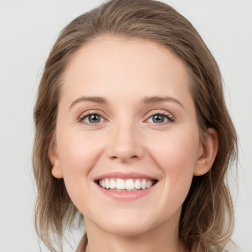 Joyful white young-adult female with medium  brown hair and grey eyes