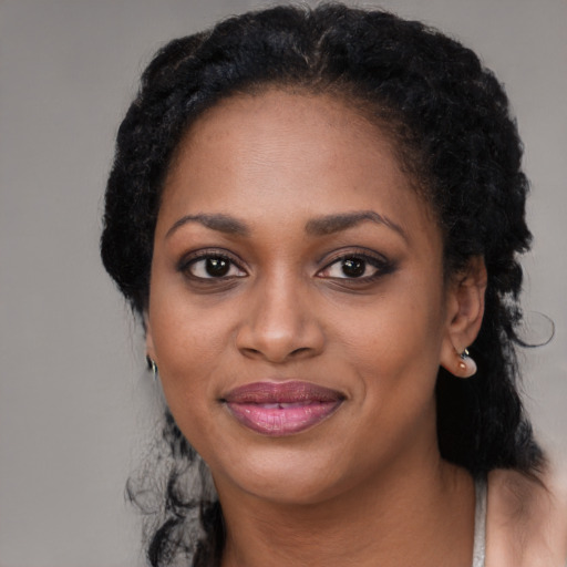 Joyful black young-adult female with long  black hair and brown eyes