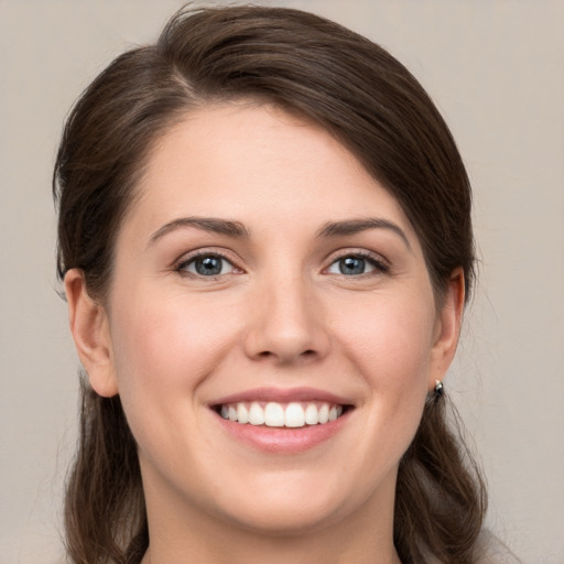 Joyful white young-adult female with long  brown hair and grey eyes