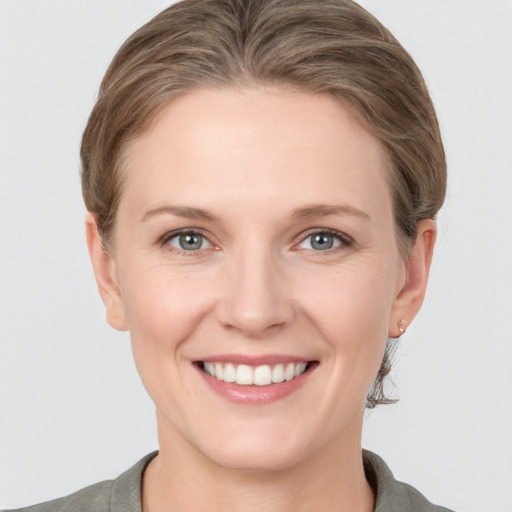 Joyful white young-adult female with medium  brown hair and grey eyes