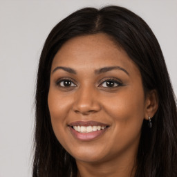 Joyful black young-adult female with long  brown hair and brown eyes