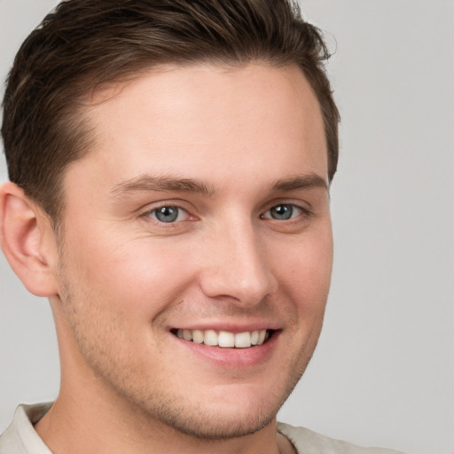 Joyful white young-adult male with short  brown hair and grey eyes