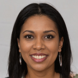 Joyful black young-adult female with long  brown hair and brown eyes