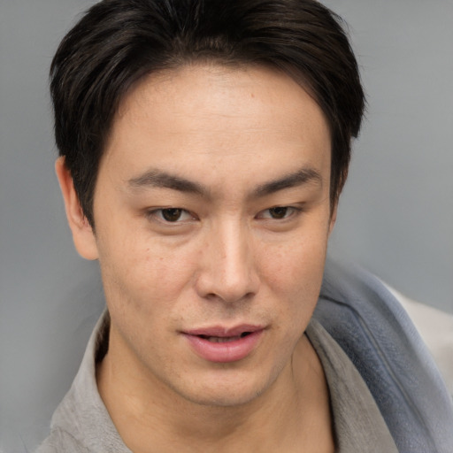 Joyful asian young-adult male with short  brown hair and brown eyes