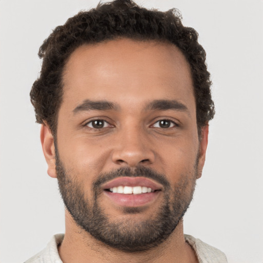 Joyful black young-adult male with short  brown hair and brown eyes