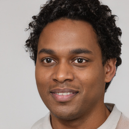 Joyful black young-adult male with short  black hair and brown eyes