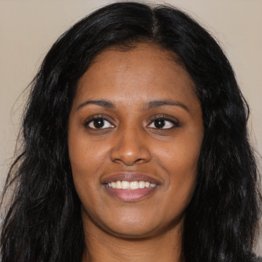 Joyful black young-adult female with long  black hair and brown eyes