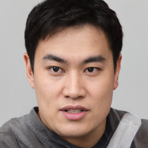 Joyful white young-adult male with short  black hair and brown eyes