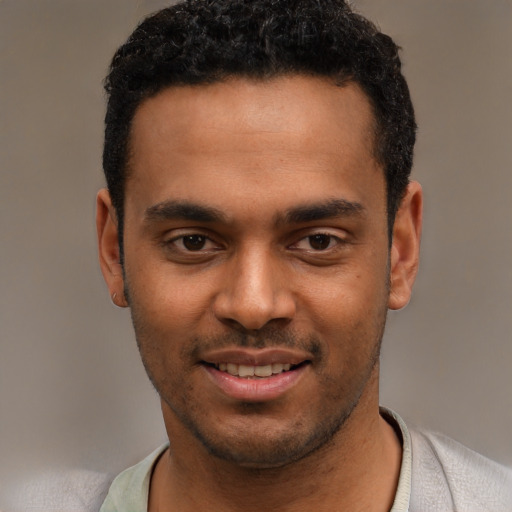 Joyful black young-adult male with short  black hair and brown eyes