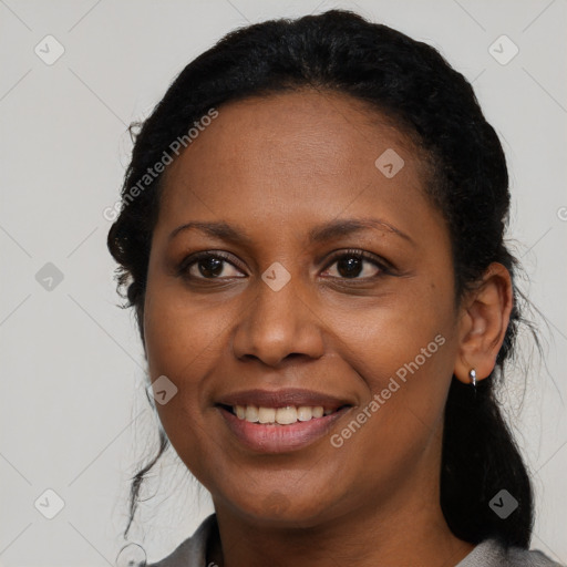 Joyful black young-adult female with long  black hair and brown eyes