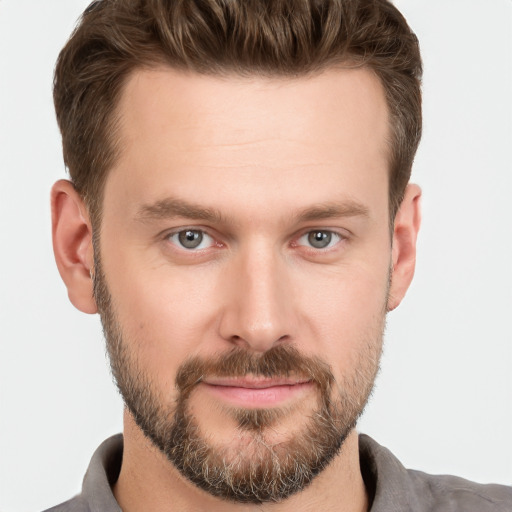 Joyful white young-adult male with short  brown hair and grey eyes