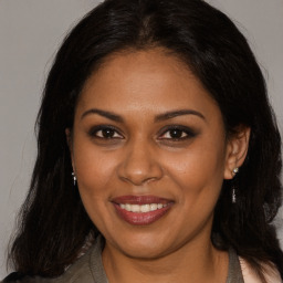 Joyful black young-adult female with long  brown hair and brown eyes