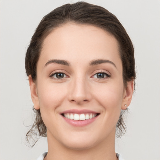 Joyful white young-adult female with medium  brown hair and grey eyes