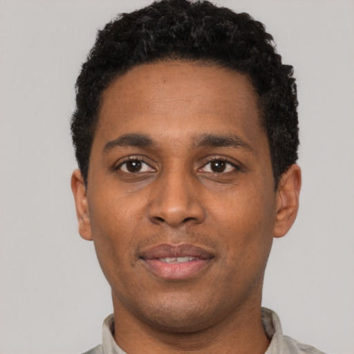 Joyful black young-adult male with short  black hair and brown eyes