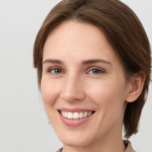 Joyful white young-adult female with medium  brown hair and grey eyes