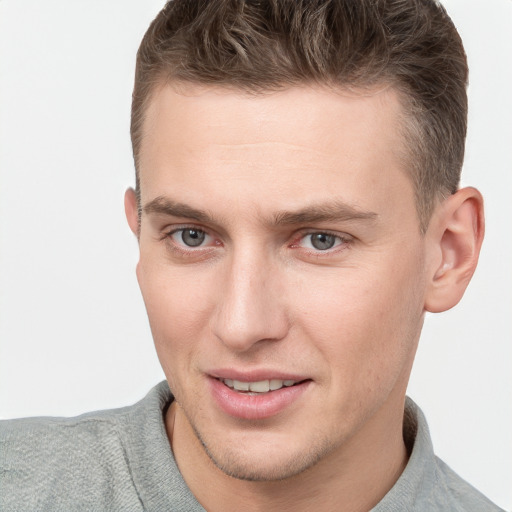 Joyful white young-adult male with short  brown hair and grey eyes