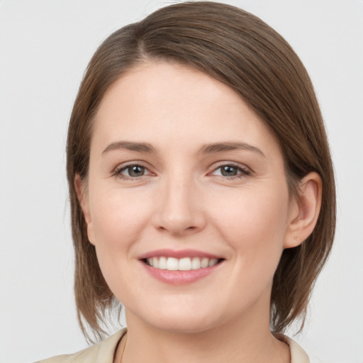 Joyful white young-adult female with medium  brown hair and grey eyes