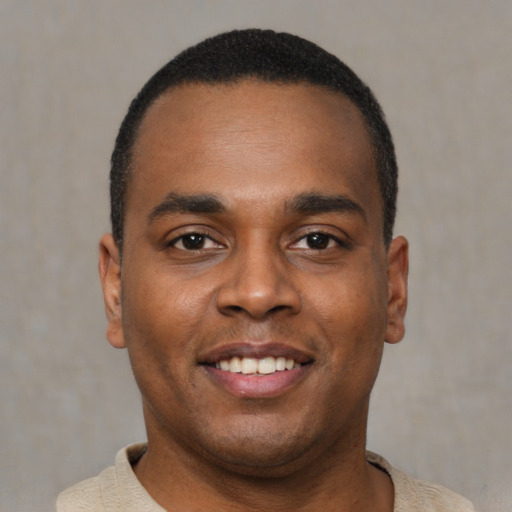 Joyful black young-adult male with short  brown hair and brown eyes