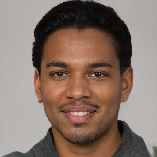 Joyful black young-adult male with short  brown hair and brown eyes
