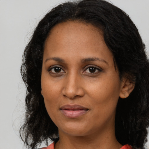Joyful black adult female with long  brown hair and brown eyes