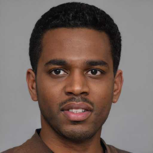 Joyful black young-adult male with short  black hair and brown eyes