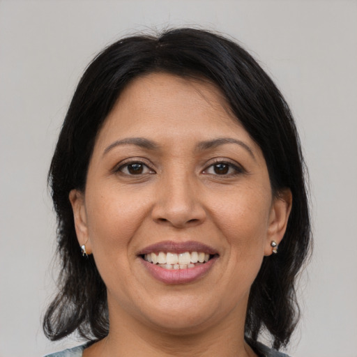 Joyful latino adult female with medium  brown hair and brown eyes