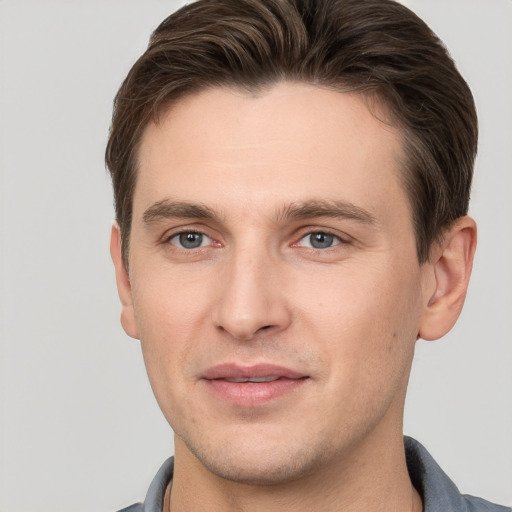 Joyful white young-adult male with short  brown hair and grey eyes