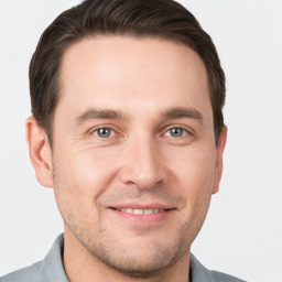 Joyful white young-adult male with short  brown hair and grey eyes