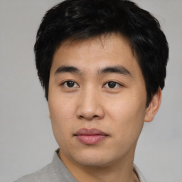 Joyful asian young-adult male with short  black hair and brown eyes