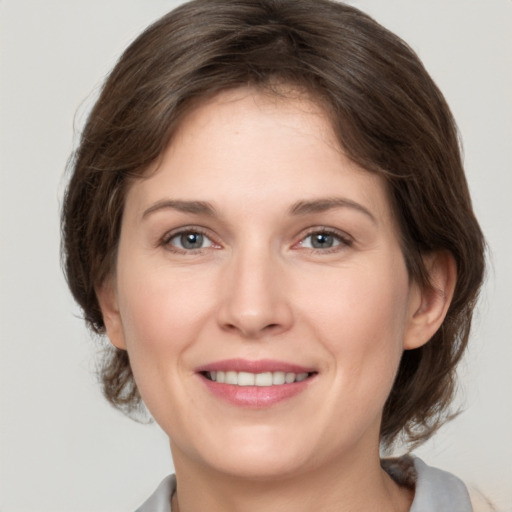 Joyful white young-adult female with medium  brown hair and grey eyes