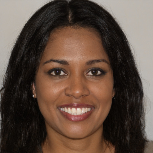 Joyful black young-adult female with long  brown hair and brown eyes