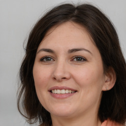 Joyful white young-adult female with long  brown hair and brown eyes