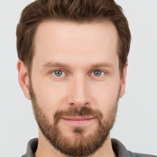 Joyful white young-adult male with short  brown hair and grey eyes