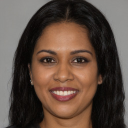 Joyful black young-adult female with long  brown hair and brown eyes