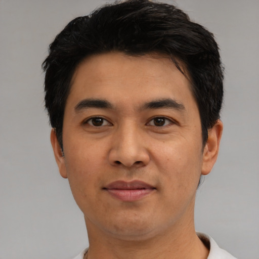 Joyful latino young-adult male with short  black hair and brown eyes