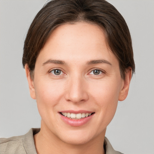 Joyful white young-adult female with short  brown hair and grey eyes