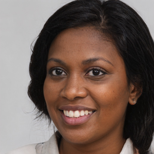 Joyful black young-adult female with long  brown hair and brown eyes