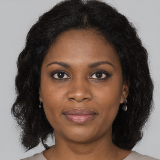 Joyful black young-adult female with long  black hair and brown eyes