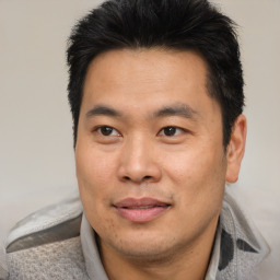 Joyful asian adult male with short  black hair and brown eyes
