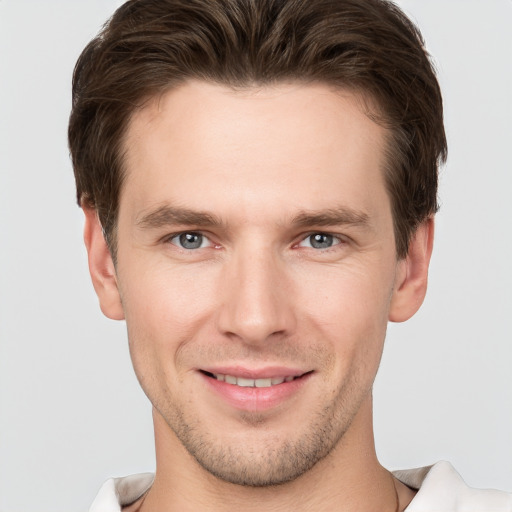 Joyful white young-adult male with short  brown hair and grey eyes