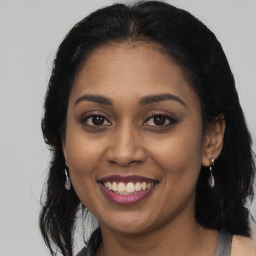 Joyful black young-adult female with long  brown hair and brown eyes