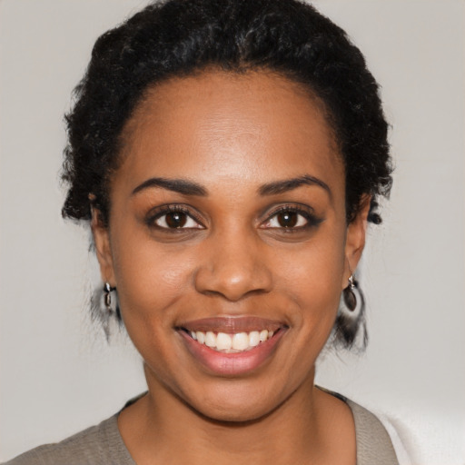 Joyful black young-adult female with short  black hair and brown eyes