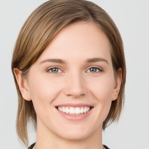 Joyful white young-adult female with medium  brown hair and grey eyes