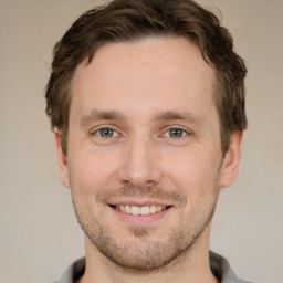 Joyful white young-adult male with short  brown hair and grey eyes