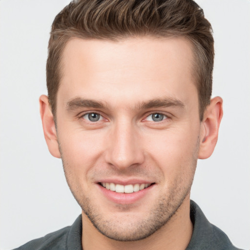 Joyful white young-adult male with short  brown hair and grey eyes