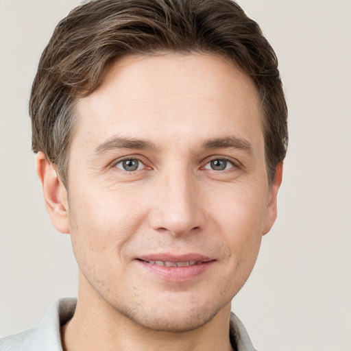 Joyful white young-adult male with short  brown hair and grey eyes